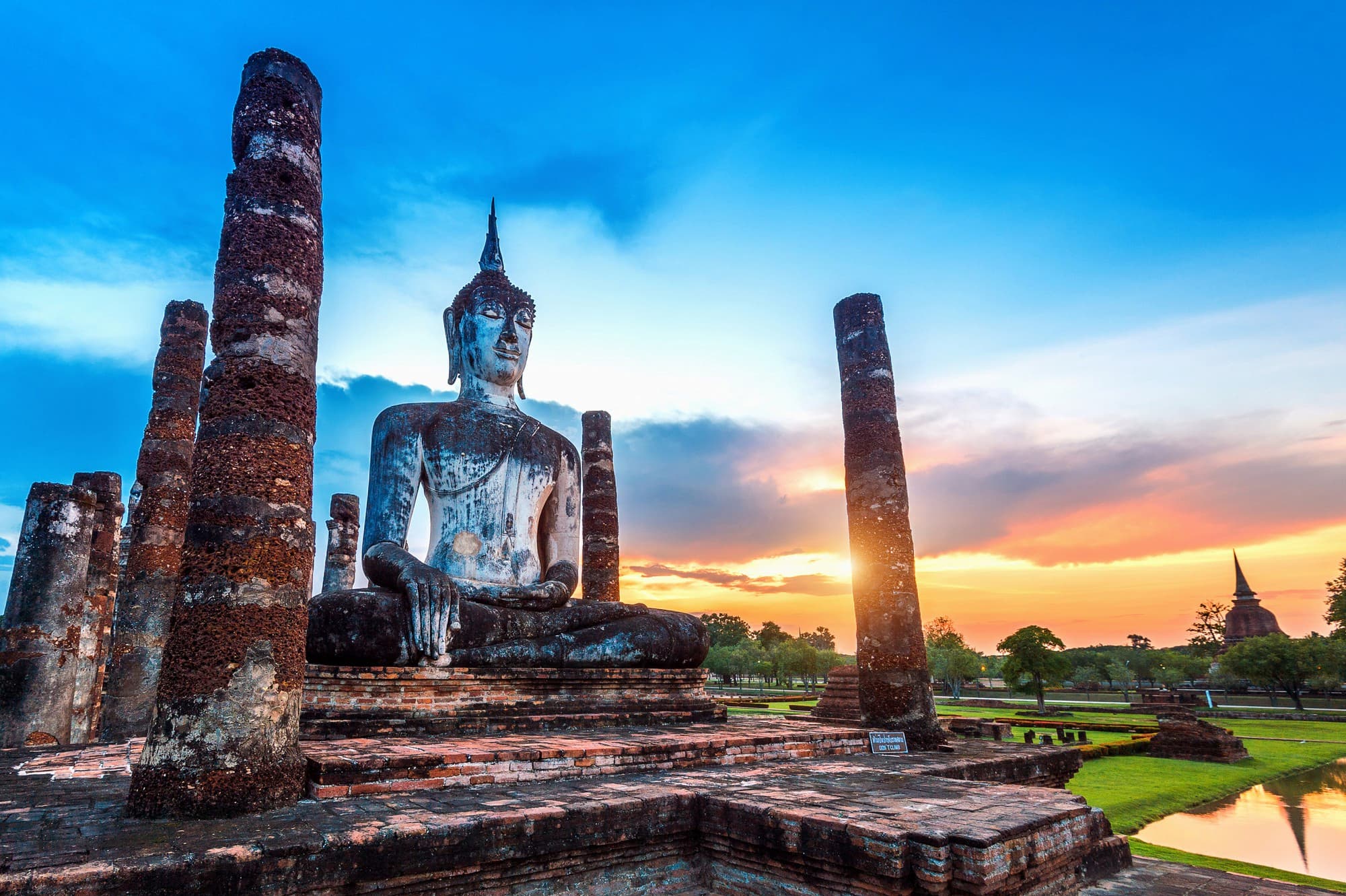 A Buddhist statue atop a brick plinth with stone columns around it.