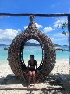 A girl sat in a bathing suit inside a small handmade seating pod/area