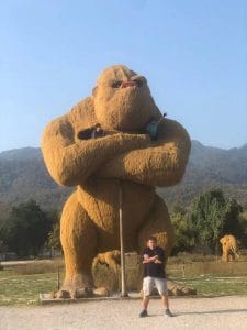 A large play gorilla with children at the top and a man stood imitating the gorilla's pose in front of it.
