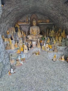 An arrangement of Buddhist statues, religious objects and figurines arranged in a small shrine.